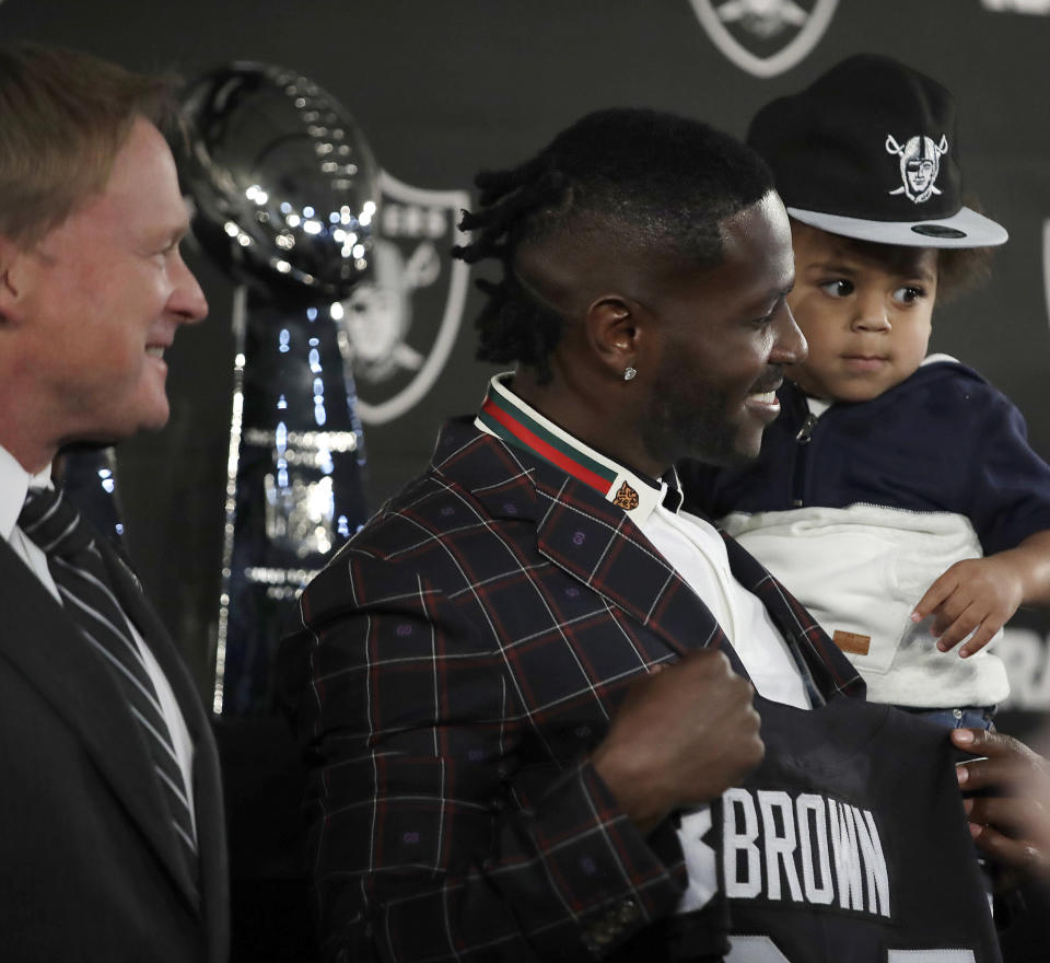 Oakland Raiders wide receiver Antonio Brown, center, holds his son Apollo beside coach Jon Gruden, left, after an NFL news conference Wednesday, March 13, 2019, in Alameda, Calif. (AP Photo/Ben Margot)