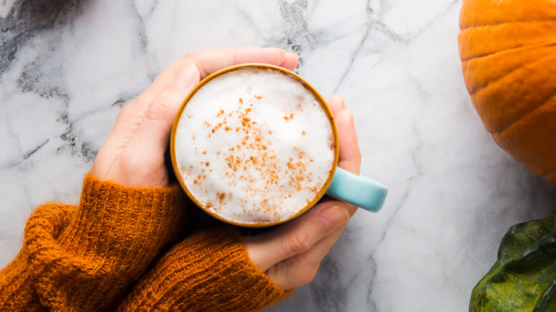 hands holding pumpkin spice latte