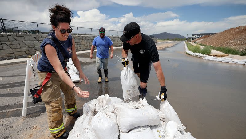Santaquin firefighter Amber Cummings, Santaquin Fire Capt. Kyle Pace and Santaquin Fire Capt. Corey Houskeeper set up sandbags to contain flooding in Santaquin on Wednesday, May 17, 2023.