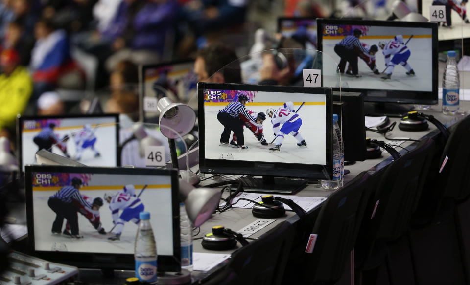 Austria and Norway facing off are seen on television screens in the press tribune during the first period of a men's ice hockey game at the 2014 Winter Olympics, Sunday, Feb. 16, 2014, in Sochi, Russia. (AP Photo/Julio Cortez)