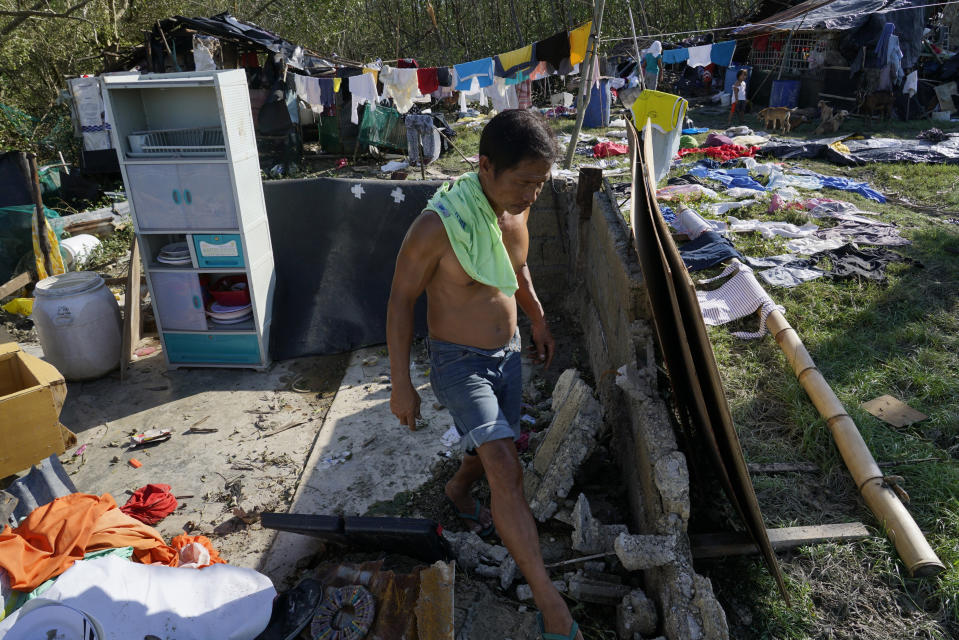 A man walks amid damaged homes following Typhoon Rai in Talisay, Cebu province, central Philippines on Saturday, Dec. 18, 2021. The strong typhoon engulfed villages in floods that trapped residents on roofs, toppled trees and knocked out power in southern and central island provinces, where more than 300,000 villagers had fled to safety before the onslaught, officials said. (AP Photo/Jay Labra)