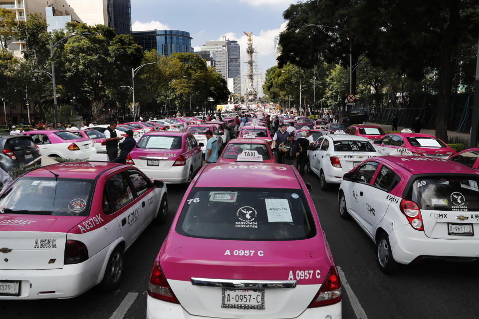 Hundreds of taxi drivers gather round the Angel of Independence monument to protest ride apps, in Mexico City, Monday, Oct. 7, 2019. The protesters want the apps banned, arguing that the apps are unfair competition because those drivers are more loosely regulated and don't have to pay licensing fees. (AP Photo/Marco Ugarte)