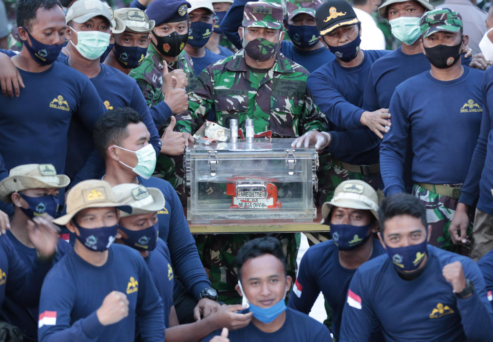 Indonesian Navy personnel pose for photos with the flight data recorder recovered from the wreckage of Sriwijaya Air flight SJ-182 in the Java Sea at Tanjung Priok Port, Tuesday, Jan. 12, 2021. Indonesian navy divers searching the ocean floor on Tuesday recovered the flight data recorder from a Sriwijaya Air jet that crashed into the Java Sea with 62 people on board, Saturday, Jan. 9, 2021. (AP Photo/Dita Alangkara)