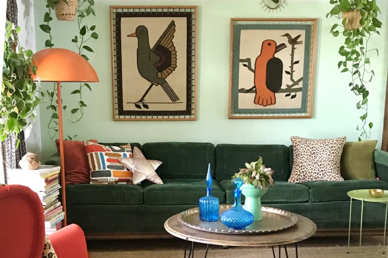 mint green boho living room with dark green sofa and boho art