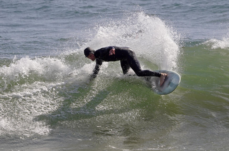 A surfer rides a wave at County Line Beach during the coronavirus outbreak, Thursday, April 2, 2020, in Malibu, Calif. The new coronavirus causes mild or moderate symptoms for most people, but for some, especially older adults and people with existing health problems, it can cause more severe illness or death. (AP Photo/Mark J. Terrill)