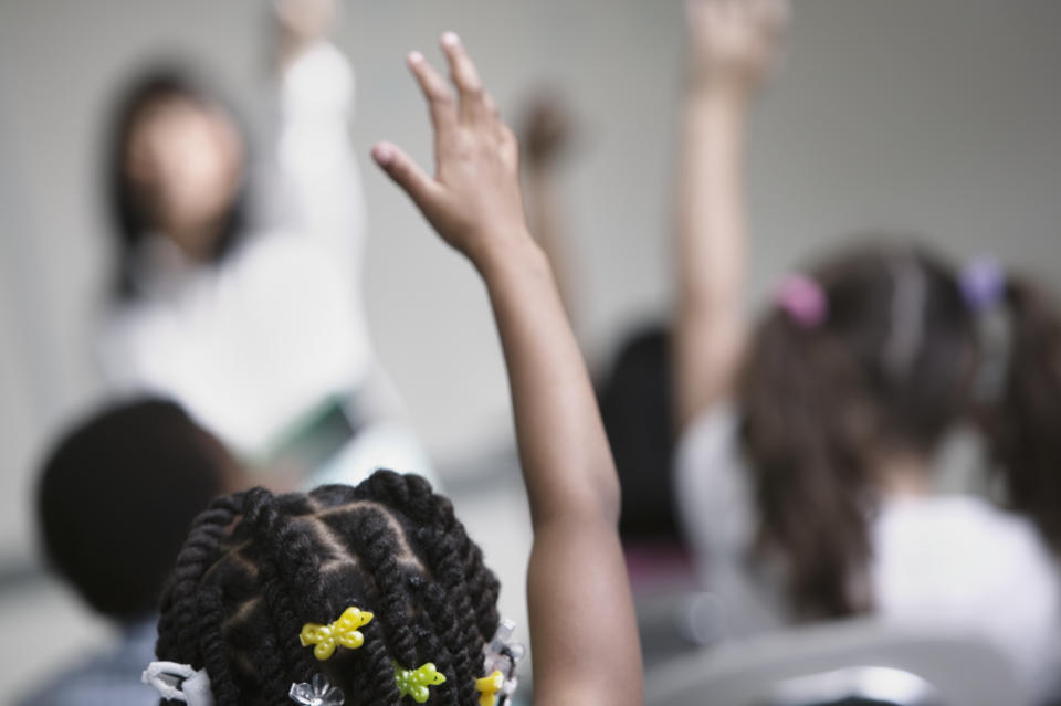 Young girl raising her hand in class