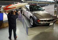 A man photographs the Glastron GT-150 Jump Boat from the 1973 Bond film "Live and Let Die" with the BMW 750iL from the 1997 film "Tomorrow Never Dies" at the opening of a press preview of the Bond in Motion exhibition at the Beaulieu National Motor Museum at Brockenhurst in the southern English county of Hampshire on January 15, 2012. The Bond in Motion exhbition features fifty original iconic vehicles used in the James Bond films to celebrate fifty years of 007 and will open to the public from January 17. AFP PHOTO / JUSTIN TALLIS