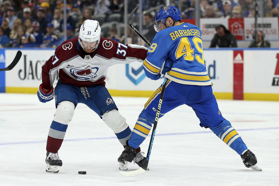 Colorado Avalanche's J.T. Compher (37) and St. Louis Blues' Ivan Barbashev (49) vie for a loose puck during the third period of an NHL hockey game Saturday, Feb. 18, 2023, in St. Louis. (AP Photo/Scott Kane)