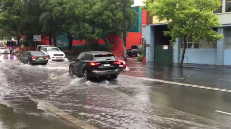 Vehicles drive on a flooded street in Sydney, New South Wales, Australia November 28, 2018 in this still image taken from a video obtained from social media. @DeeCee451/via REUTERS