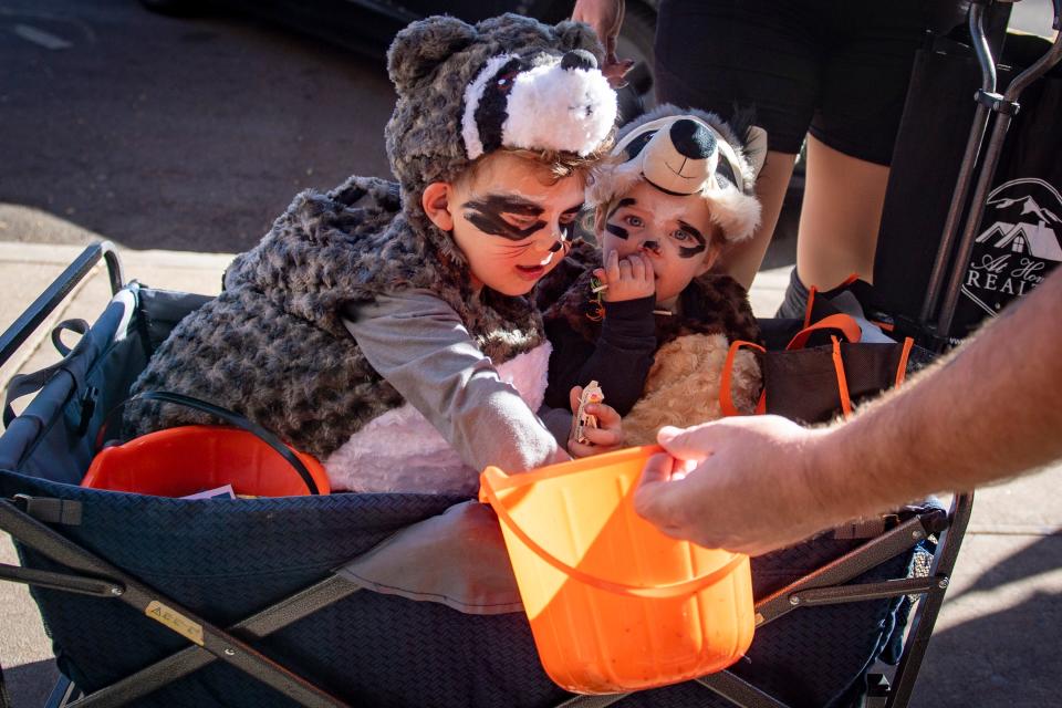 Fennir Lilly, 4, left, and Mina Lilly, 1, of Fort Collins, collect candy from Max Blehm, general manager at The Bar District, during Tiny Tot Halloween in Old Town Fort Collins on Monday, Oct. 31, 2022.