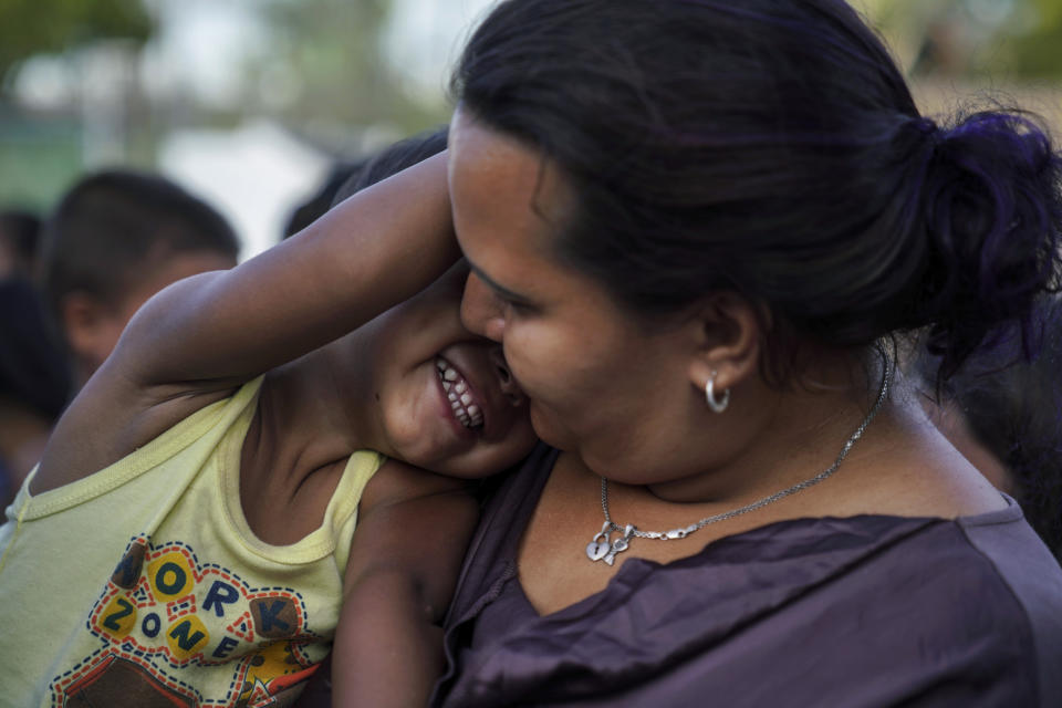 In this Aug. 30, 2019, photo, a Honduran mother plays with her son as they wait in line to get a meal in an encampment near the Gateway International Bridge in Matamoros, Mexico. They had been sent back to wait for their asylum case in Mexico under the "Remain in Mexico" program, officially called the Migrant Protection Protocols. (AP Photo/Veronica G. Cardenas)