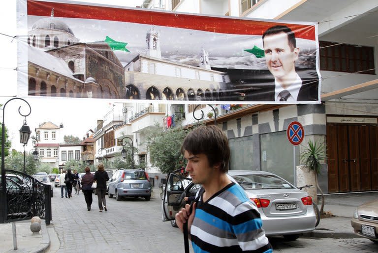 A man walks under a banner depicting Syrian President Bashar al-Assad as he crosses a road in old Damascus on April 30. The Syrian authorities have set a deadline of 15 days for people who had committed "unlawful acts" to give themselves up, as a wave of arrests was reported across the country