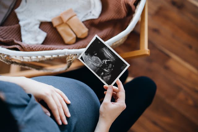 <p>Getty</p> Stock image of pregnant woman looking at ultrasound photo as she packs her bag