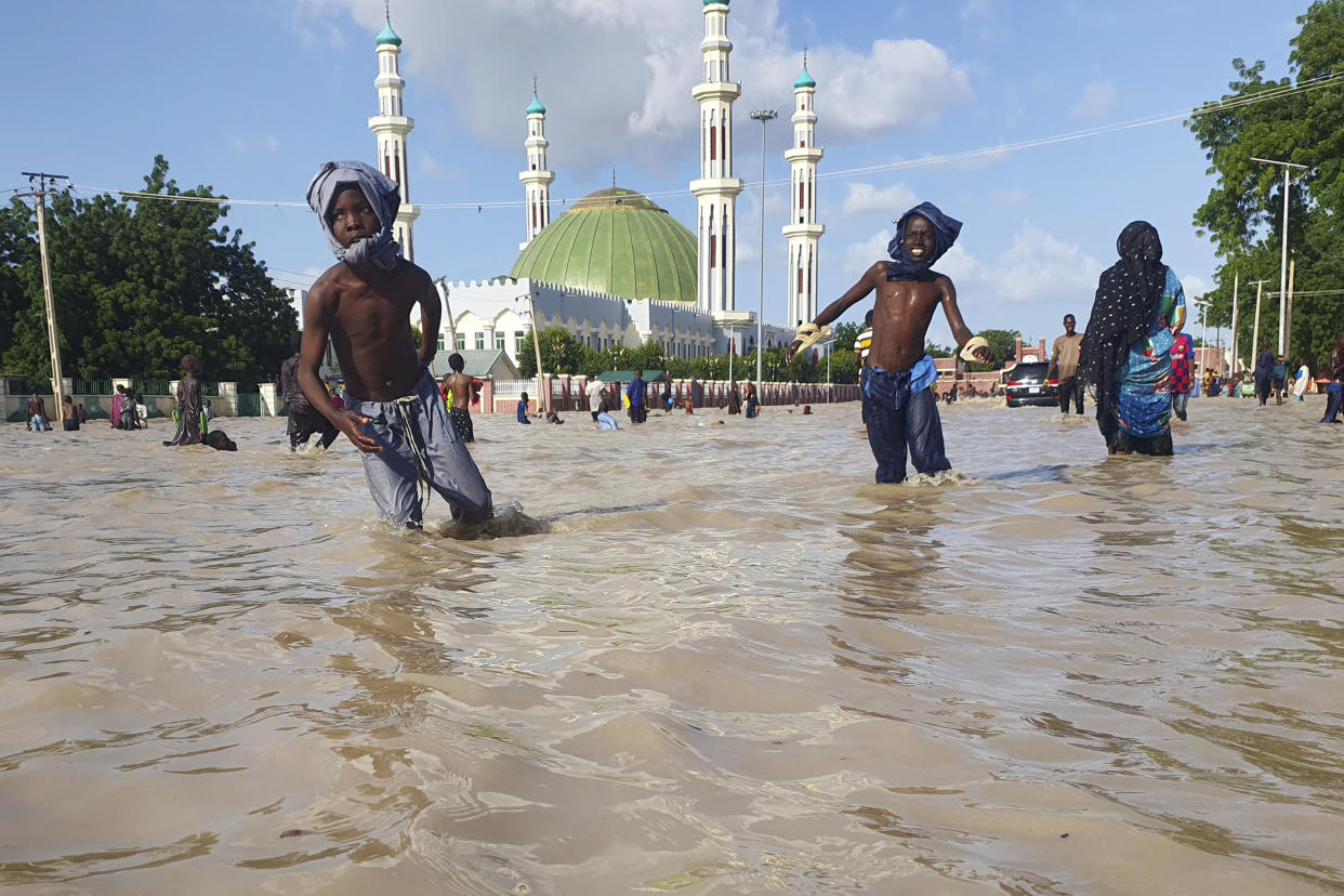 People walk through floodwaters following a dam collapse in Maiduguri, Nigeria, Tuesday Sept 10, 2024. (AP Photos/ Joshua Olatunji)