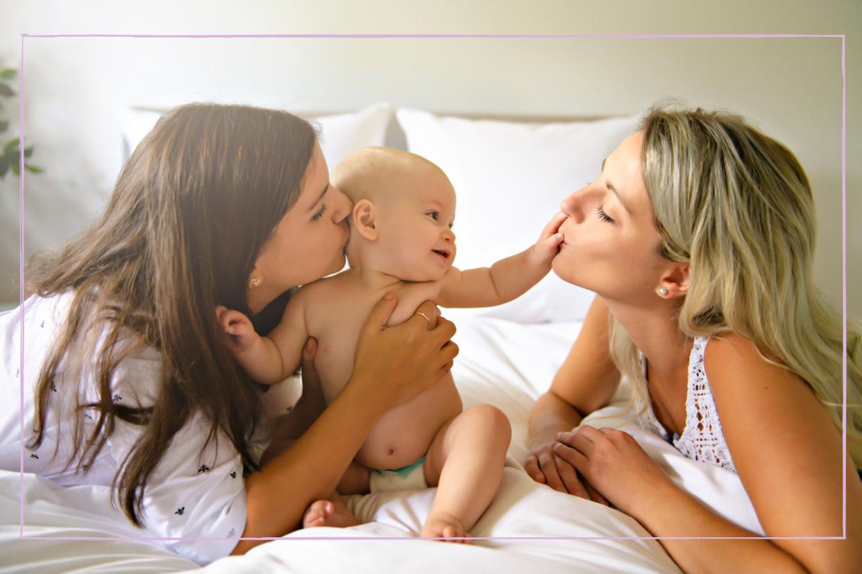  Two mums kissing and playing with their baby. 