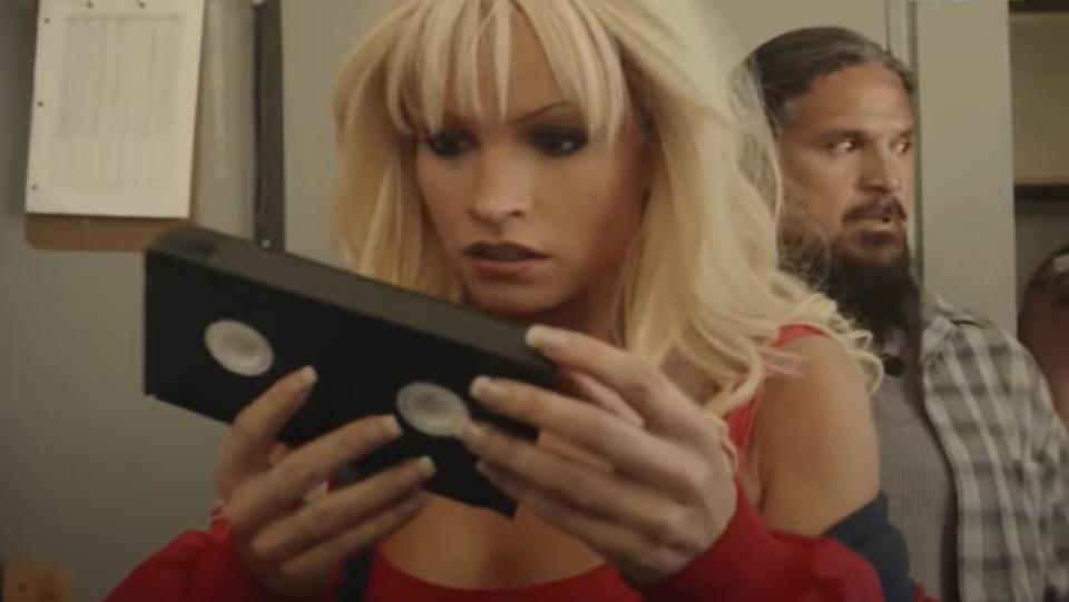 Lily James as Pam Anderson looks at a VHS tape.