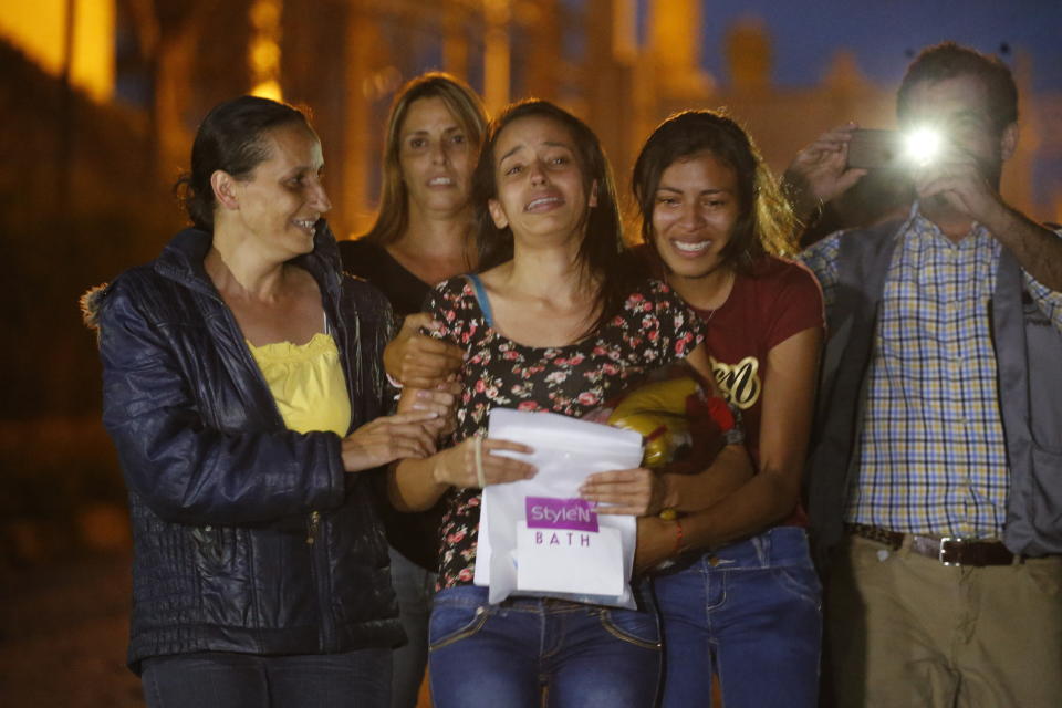 Karen Palacios, center, is helped by family members after she was released from prison at Los Teques on the outskirts of Caracas, Venezuela, Tuesday, July 16, 2019. Palacios who plays the clarinet and was cut from the National Philharmonic for criticizing the government, was detained for 6 weeks. (AP Photo/Ariana Cubillos)