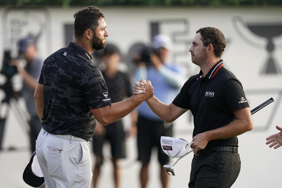 Jon Rahm of Spain, left, shakes hands with Patrick Cantlay on the 18th green during the third round of the Tour Championship golf tournament Saturday, Sept. 4, 2021, at East Lake Golf Club in Atlanta. (AP Photo/Brynn Anderson)