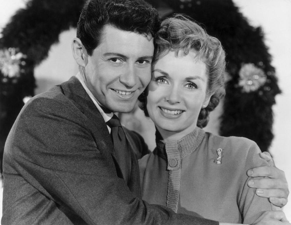 <p>After welcoming their first child together the year before, Debbie Reynolds and Eddie Fisher shared with fans a seasonal photo of the two of them in front of a giant wreath. </p>