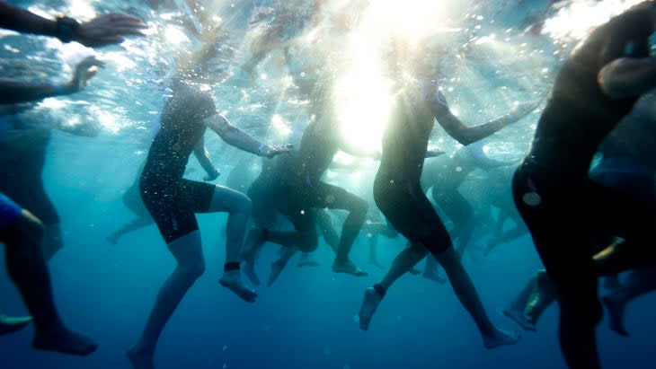 a bunch of woman swim and the camera is underwater