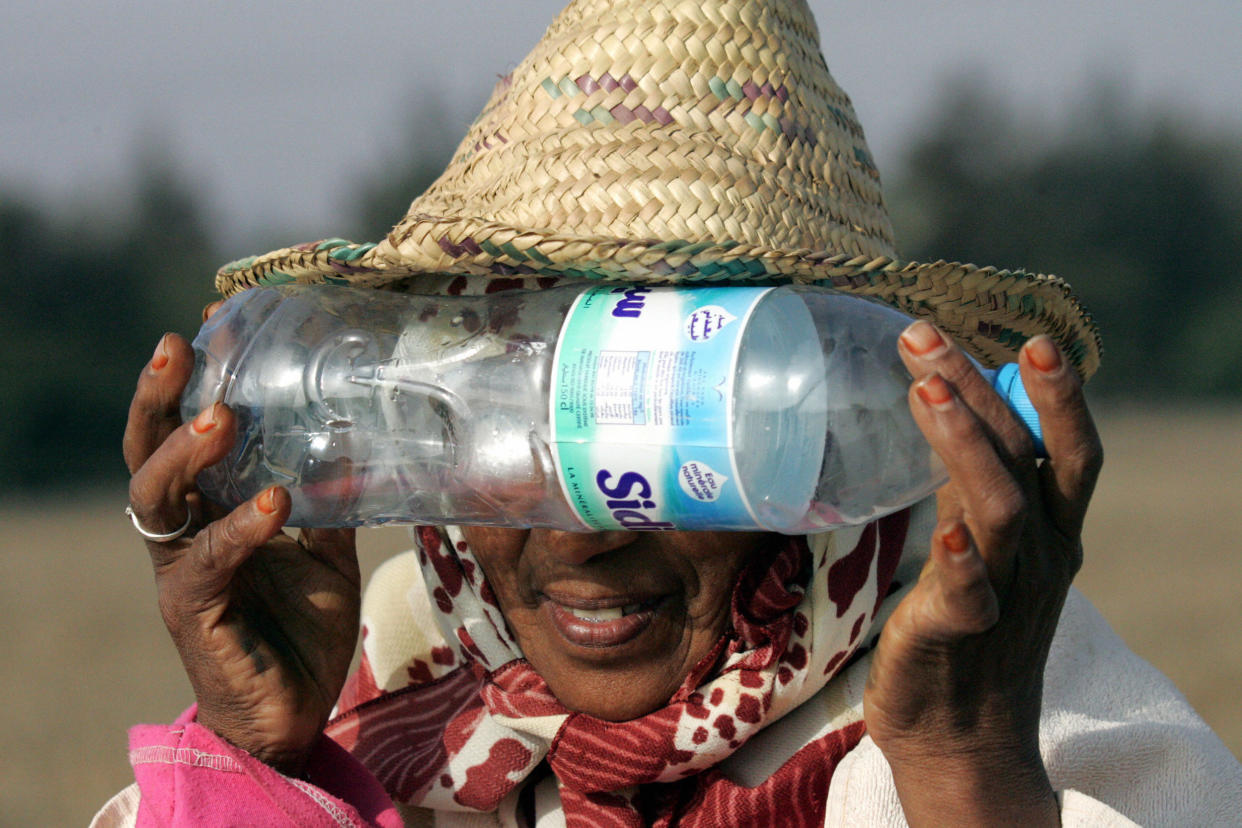 2005: A woman looks at an annular eclipse through a bottle in Rabat, Morocco.