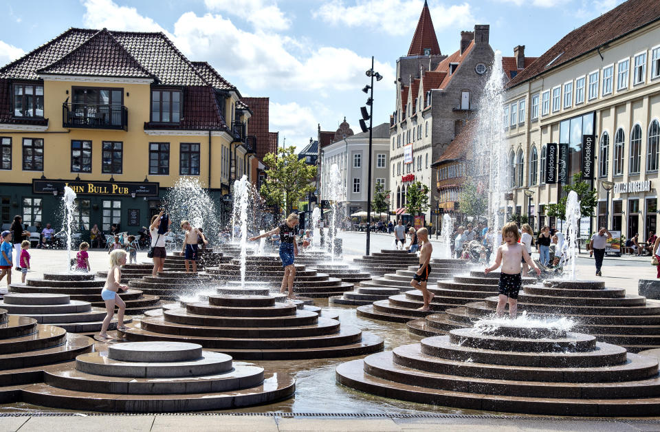 People cool down in the fountains as temperatures reached 30 degrees Celsius, at Toldbod Plads in Aalborg, Denmark, Wednesday July 24, 2019. (Henning Bagger/Ritzau Scanpix via AP)