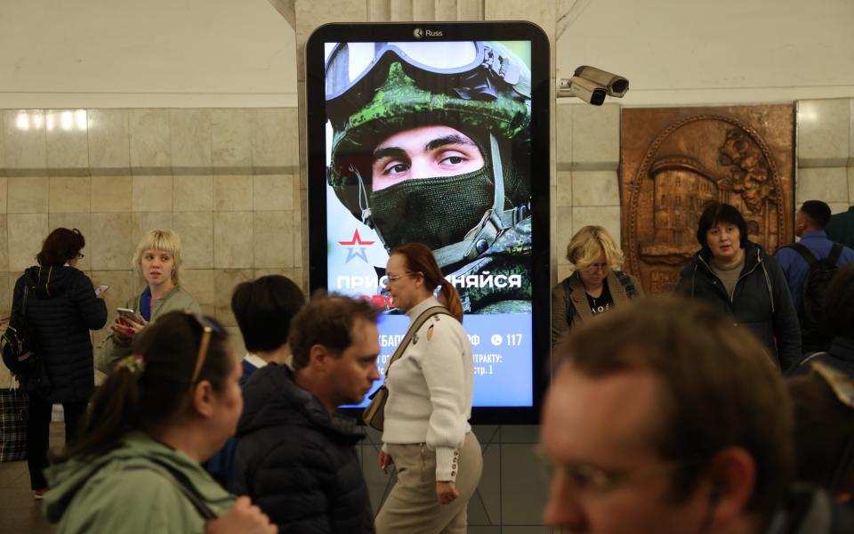 Passengers walk past a subway station billboard, advertising contract service in the army on May 12 in Moscow. - Getty
