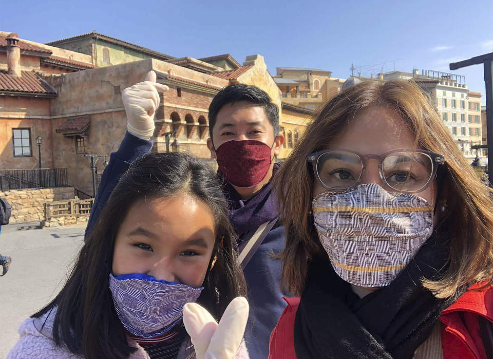 In this late February 2020, photo, Carlo Navarro poses behind his wife Evie and daughter Gia for a family photo while wearing face masks and gloves during a trip to Tokyo. When they visited Japan from the Philippines in February, they knew they were taking a chance with the coronavirus, but thought they would be spared if they took precautions. They wore masks and gloves and always had alcohol handy to sanitize their hands. Days after he was cleared and discharged from hospital, Navarro shared his COVID-19 experience on a Facebook public post. (Carlo Navarro via AP)