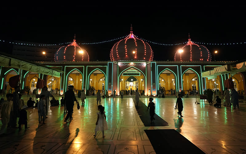 People arrive for prayer in a mosque which is decorated with lights