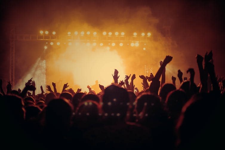 People at a concert with arms up and smoke-filled room.