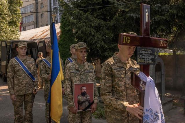 Un hombre con uniforme militar se para en un edificio destruido