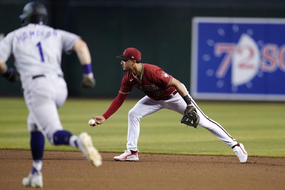 Arizona Diamondbacks second baseman Josh Rojas, right, flips the ball to second base to get out Colorado Rockies' Garrett Hampson (1) during the fourth inning of a baseball game Sunday, Aug. 7, 2022, in Phoenix. (AP Photo/Ross D. Franklin)