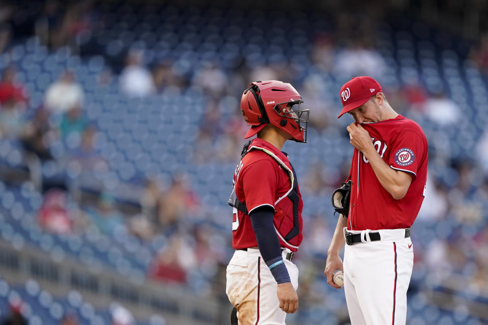 Washington Nationals starting pitcher Erick Fedde, right, visits with catcher Tres Barrera in the sixth inning of the second game of a baseball doubleheader against the Seattle Mariners, Wednesday, July 13, 2022, in Washington. Fedde was relieved in the sixth. (AP Photo/Patrick Semansky)