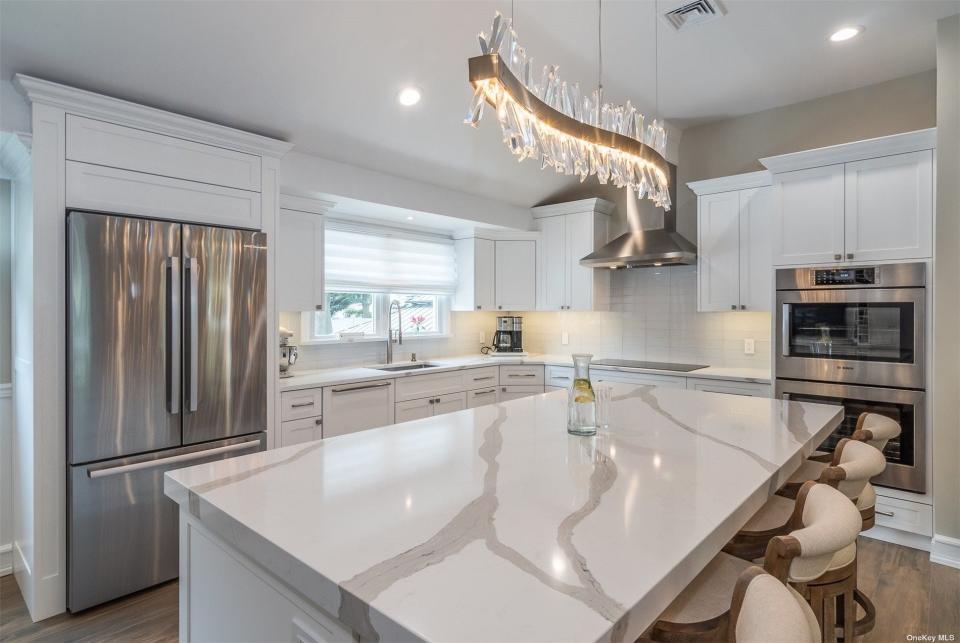 the kitchen at a house for sale in long island with marble countertops and white cabinets