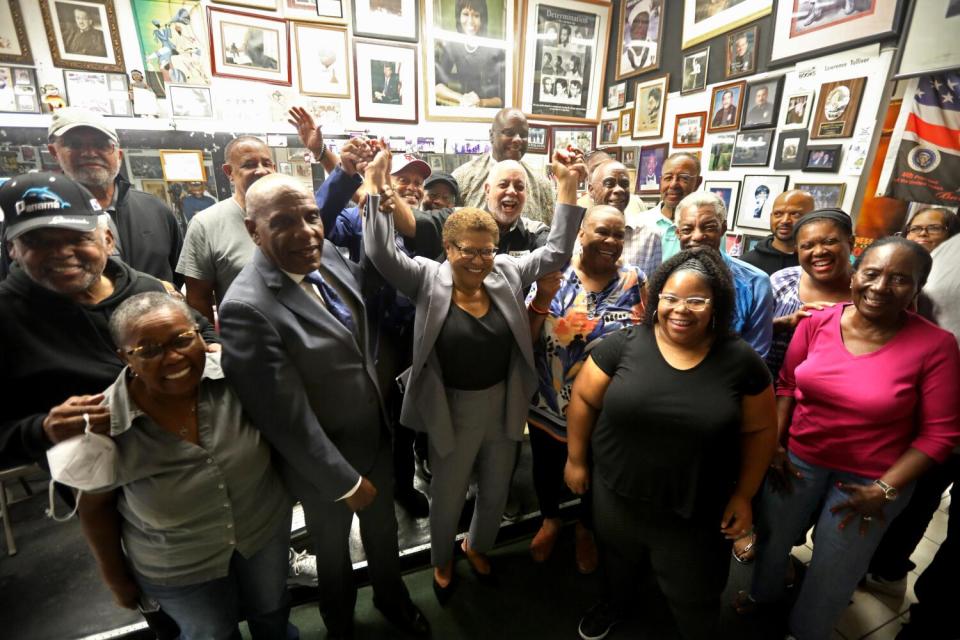 Lawrence Tolliver, center, holds Rep Karen Bass's arms up, as others show their support for Bass running for mayor