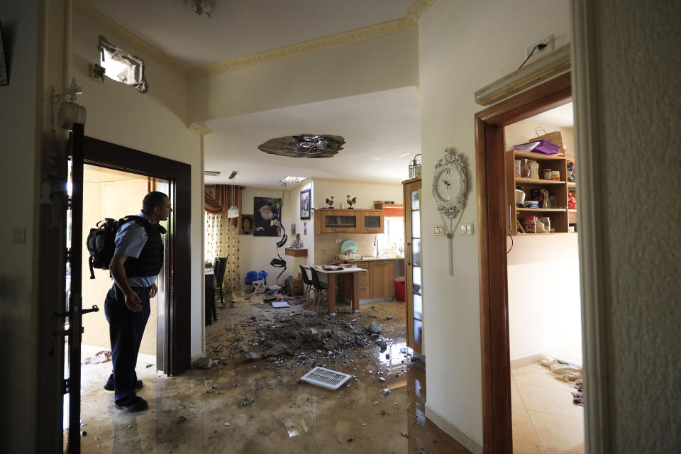 A policeman check the damage to a house hit by a rocket fired from Gaza Strip in Netivot, Israel, after it was hit by a rocket fired from Gaza Strip, Tuesday, Nov. 12m 2019. Israel has killed a senior Islamic Jihad commander in Gaza in a rare targeted killing that threatened to unleash a fierce round of cross-border violence with Palestinian militants. (AP Photo/Tsafrir Abayov)