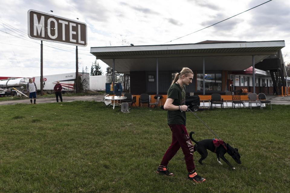 Kyan Cepin, who now resides in a motel after being displaced by the East Palestine train derailment walks his dog Opal in North Lima, Ohio, Monday, April 3, 2023. About half of East Palestine's nearly 5,000 residents evacuated when, days after the Feb. 3 derailment, officials decided to burn toxic vinyl chloride from five tanker cars to prevent a catastrophic explosion. (AP Photo/Matt Rourke)