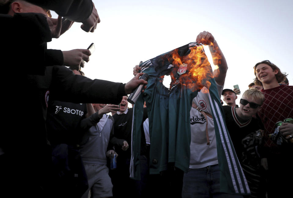 Fans burn a Liverpool replica shirt outside Elland Road, as a protest against Liverpool's decision to be included amongst the clubs attempting to form a new European Super League, in Leeds, England, Monday, April 19, 2021. Reaction to the proposals from 12 clubs to rip up European soccer by forming a breakaway Super League has ranged from anger and condemnation to humor and sarcasm. (Zac Goodwin/PA via AP)