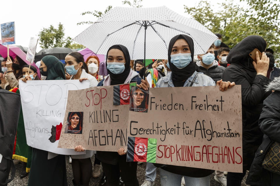 Women hold signs reading "Stop killing Afghans" and "Peace, Freedom, Justice for Afghanistan" during a demonstration for the reception of threatened people from Afghanistan, in Hamburg, Germany, Sunday Aug. 22, 2021. (Markus Scholz/dpa via AP)