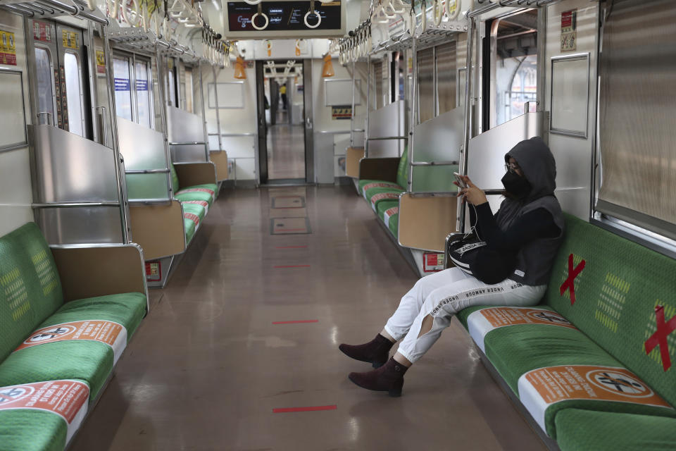 A woman wearing a face mask to curb the spread of coronavirus sits inside an empty train at the Jakarta Kota train station in Jakarta, Indonesia, Wednesday, July 28. (AP Photo/Tatan Syuflana)