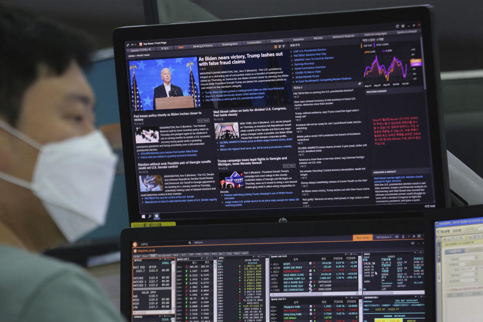 A screen shows Democratic presidential candidate former Vice President Joe Biden during a news program about the U.S. elections as a currency trader works at the foreign exchange dealing room of the KEB Hana Bank headquarters in Seoul, South Korea, Friday, Nov. 6, 2020. (AP Photo/Ahn Young-joon)