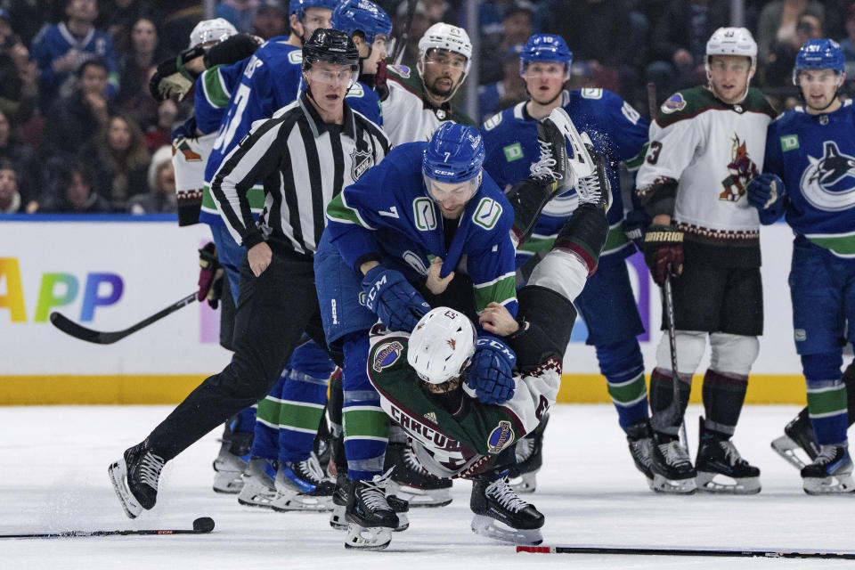 Vancouver Canucks' Carson Soucy (7) grapples with Arizona Coyotes' Michael Carcone (53) during the second period of an NHL hockey game Thursday, Jan. 18, 2024, in Vancouver, British Columbia. (Ethan Cairns/The Canadian Press via AP)