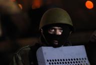 An anti-government protester watches riot police from the barricade in Kiev February 7, 2014. REUTERS/David Mdzinarishvili