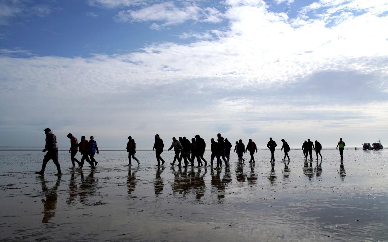 A group of people thought to be migrants walk up the beach after being brought in to Dungeness, Kent, onboard the RNLI Dungeness Lifeboat, May 17