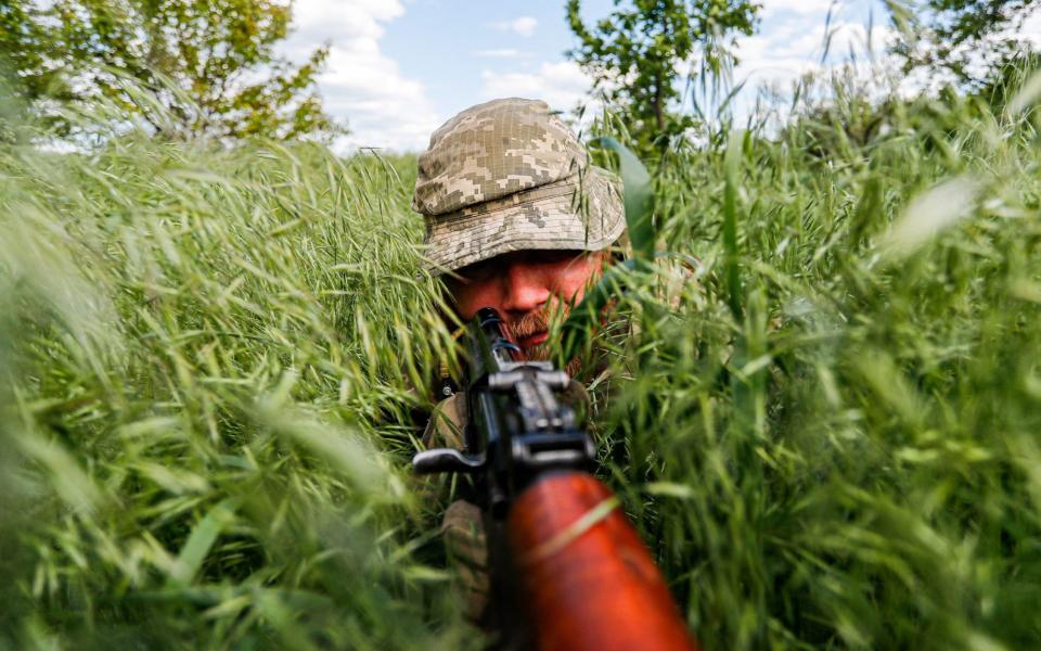 A Ukrainian soldier hides in the grass during a patrol and monitoring operation on the outskirt of the separatist region of Donetsk - Daniel Ceng Shou-Yi/ZUMA Press Wire/Shutterstock /Shutterstock 