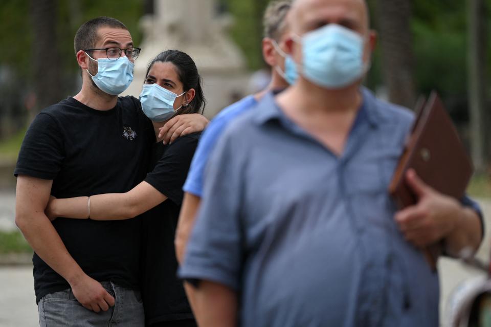 People stand in line outdoors as they wait to receive a dose of the Johnson & Johnson COVID-19 vaccine in Barcelona. 