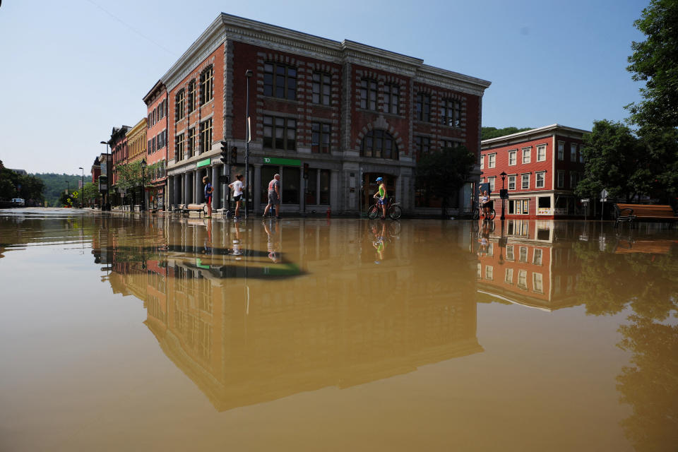 Several residents look over the damage along a flooded street.