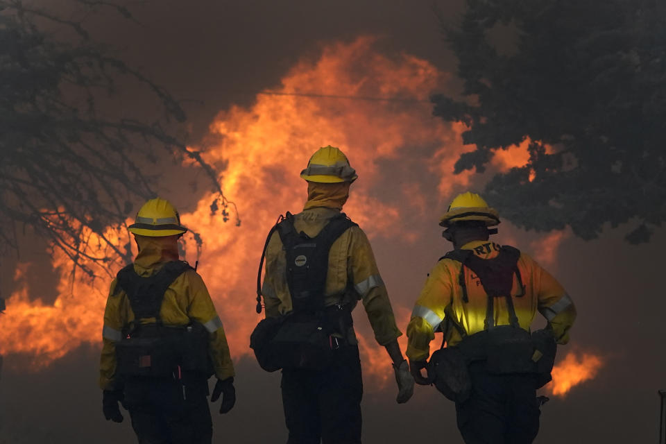 Members of a Los Angeles County Fire crew make a stand to protect a home from the advancing Bobcat Fire along Cima Mesa Rd. Friday, Sept. 18, 2020, in Juniper Hills, Calif. (AP Photo/Marcio Jose Sanchez)