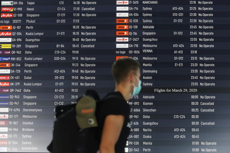 Traveller walks past a flight information board showing cancelled flights at Ngurah Rai International Airport in Bali