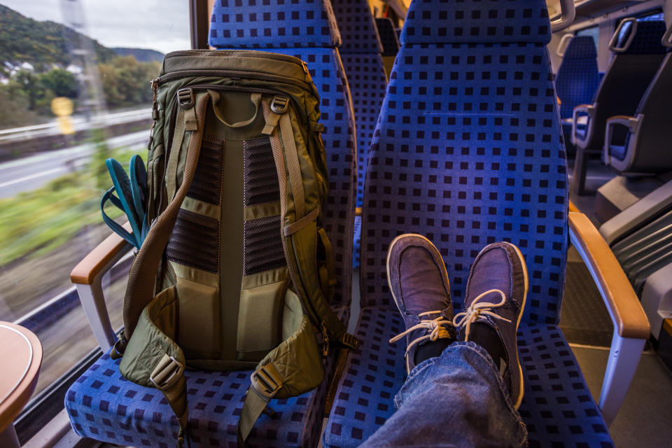 Backpacker's feet resting on seat in train